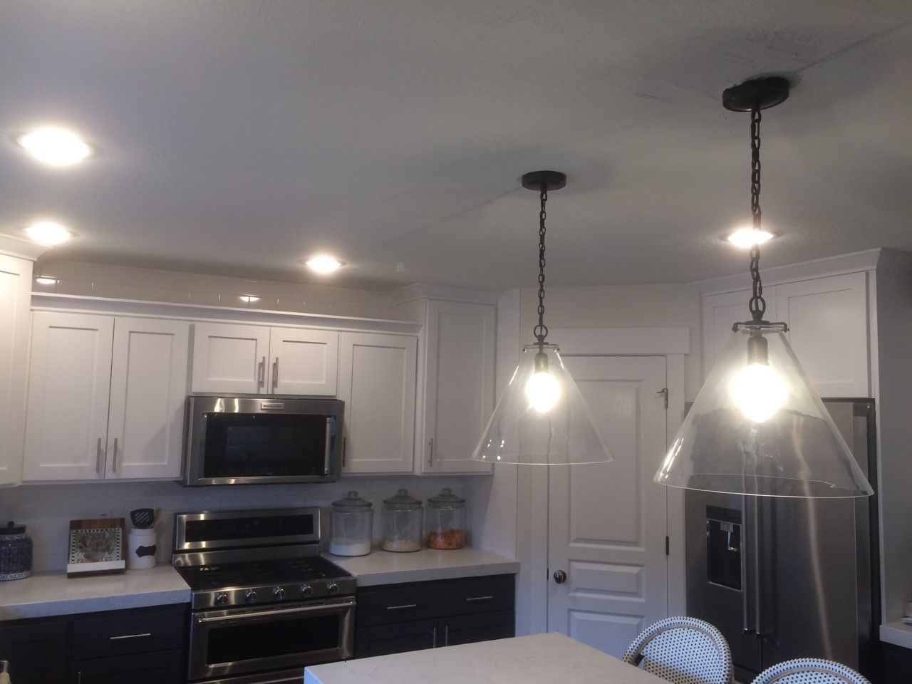 Bright kitchen with white cabinets, stainless steel appliances, and hanging pendant lights over the island