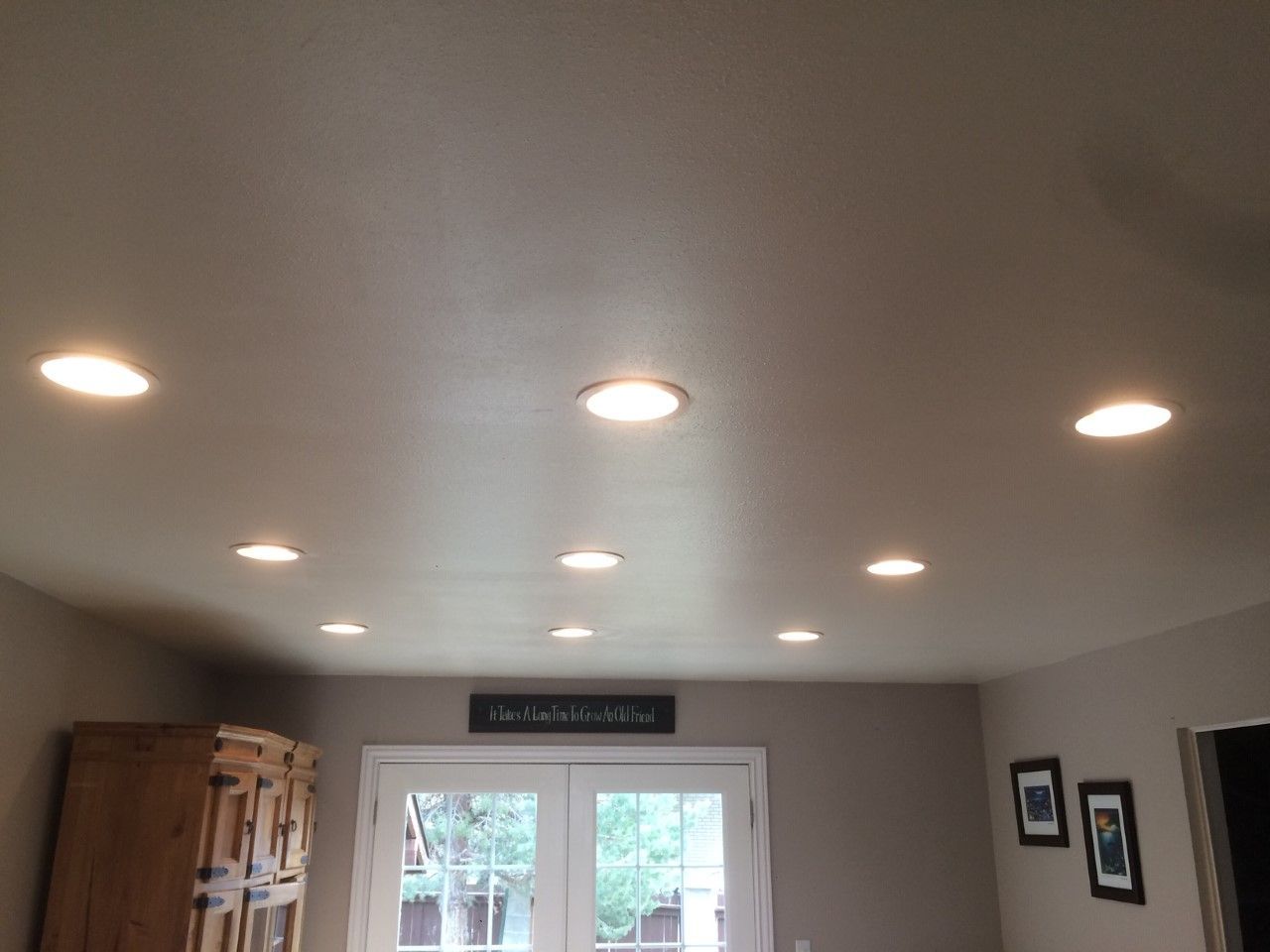 Living room ceiling with recessed lights above a window and wall decor