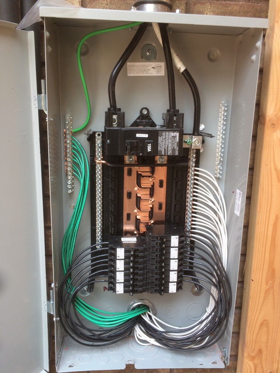 Open electrical breaker panel with copper bus bars and black/white/green wires