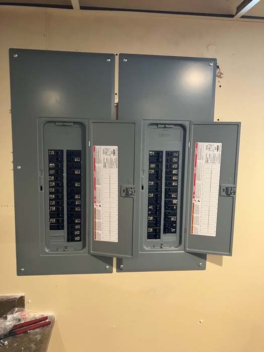 Open electrical breaker panel with two gray doors on a beige wall