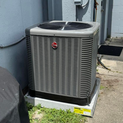 Outdoor air conditioner condenser unit on a concrete slab beside grass