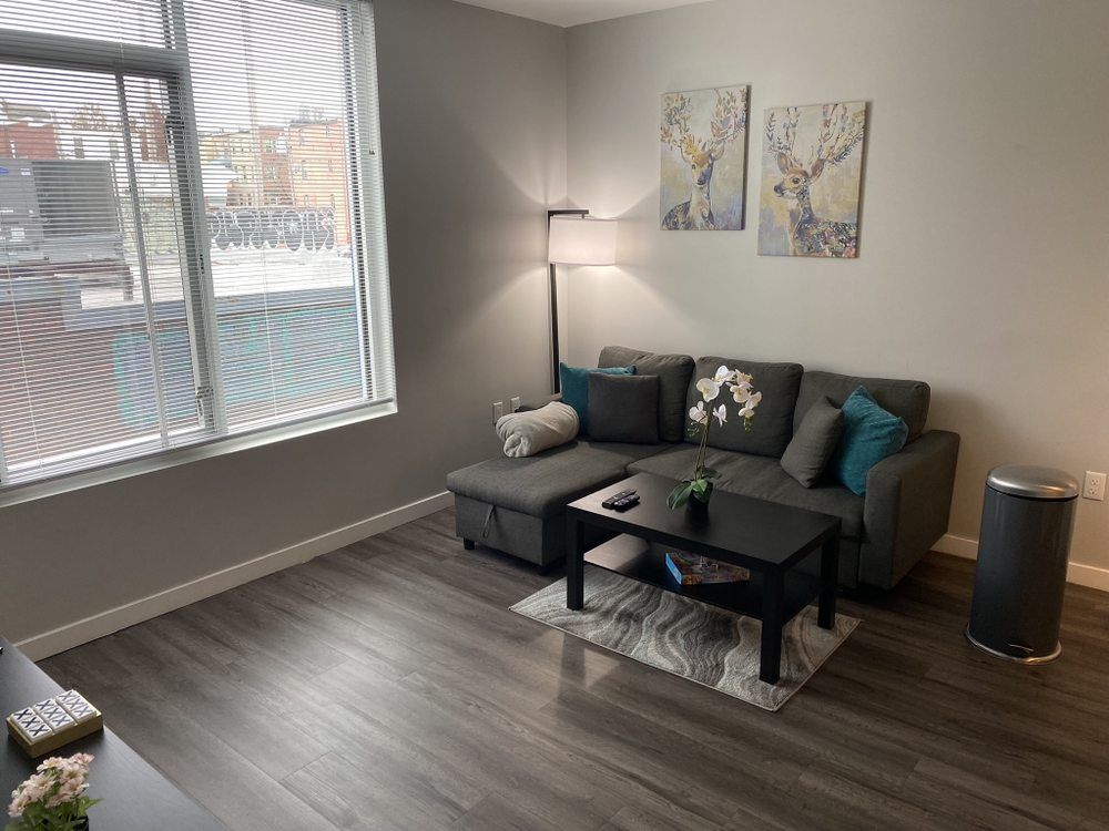 A gray sectional sofa in a living room with art, a coffee table, and a floor lamp next to a window.