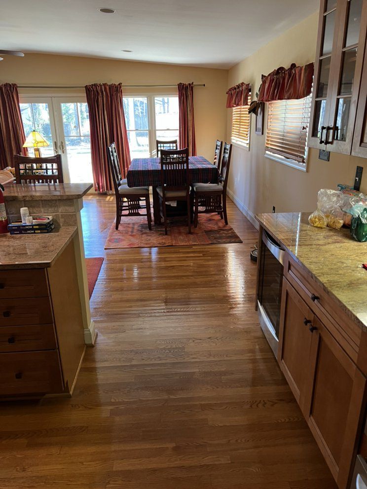 Kitchen and dining area with wooden floors, a rectangular dining table, and red curtains.