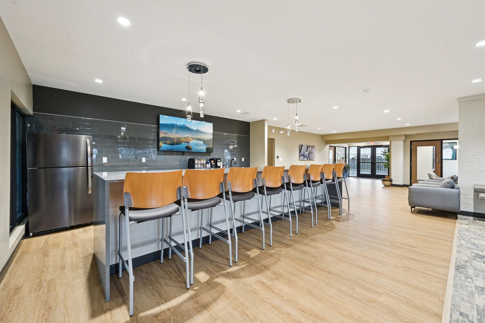 Community lounge with a long bar, tall stools, and a mounted TV.