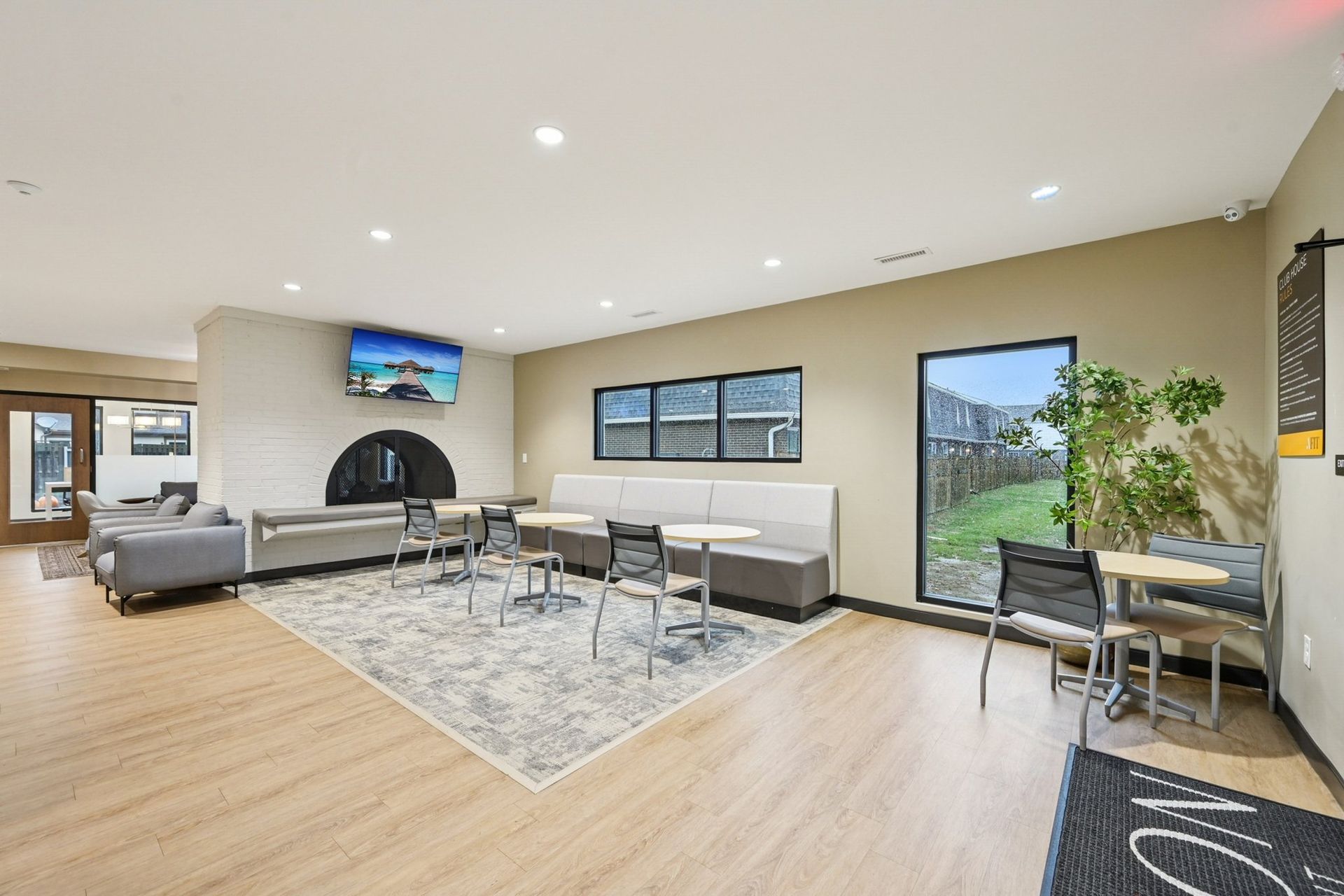 Interior common lounge with fireplace, sofas, tables, and large windows.
