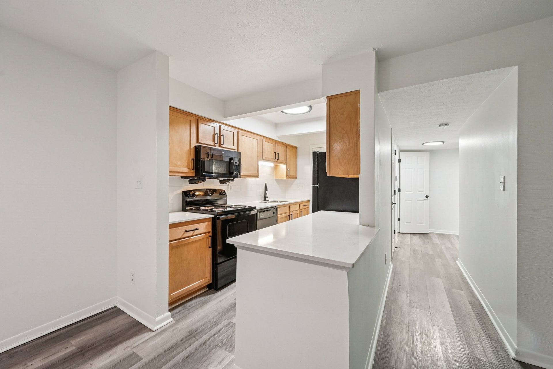 Kitchen with wooden cabinets, white countertops, and a large breakfast bar