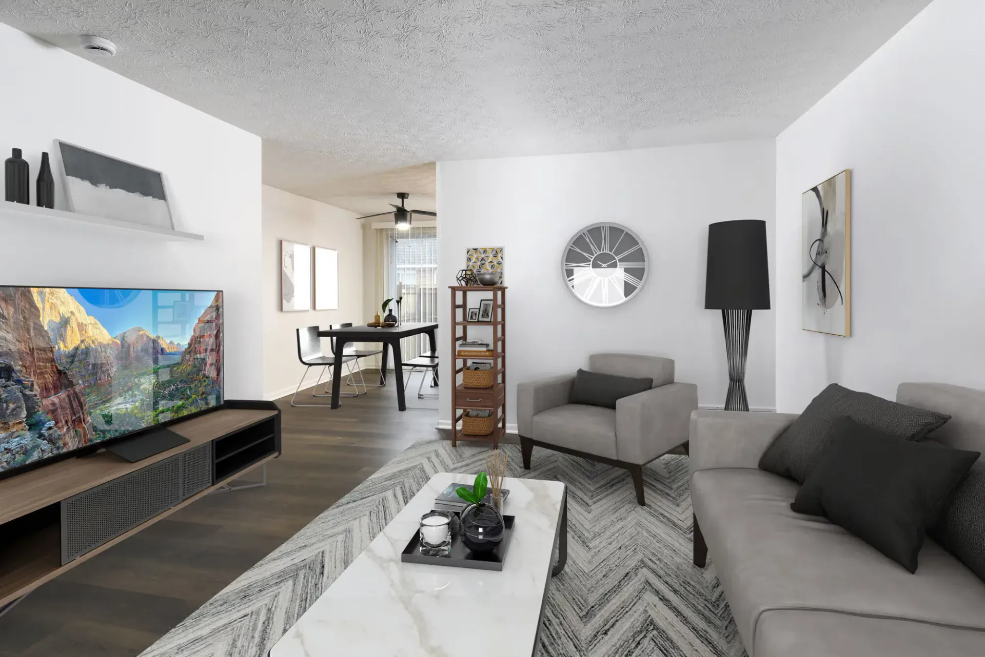Living room with gray sofa, marble coffee table, TV on a low stand, and a back dining area.