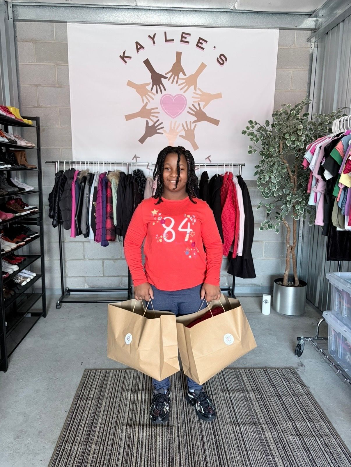 Person in red sweater holding two shopping bags in a clothing boutique