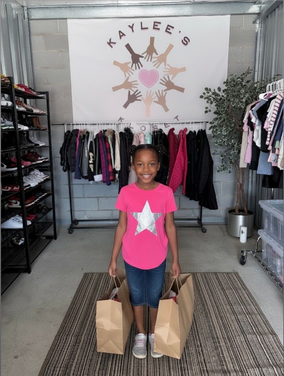 Smiling child in pink shirt standing with shopping bags in a clothing boutique