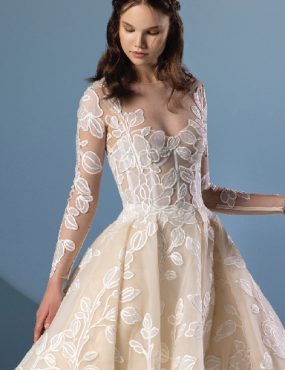 A woman is wearing a white lace wedding dress with long sleeves.