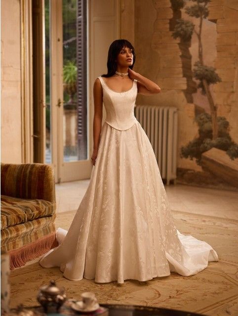 Woman in a white wedding gown standing in an elegant room with open doors and soft lighting