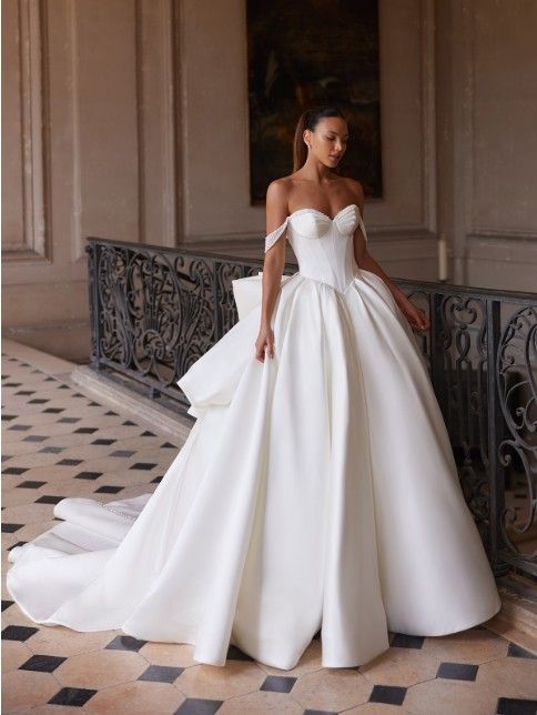 Woman in a white strapless ball gown posing in a grand hallway with ornate railings