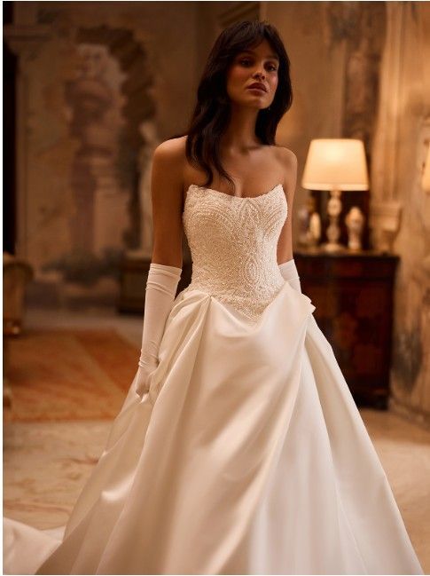 Woman in a white strapless gown standing in an elegant, softly lit room