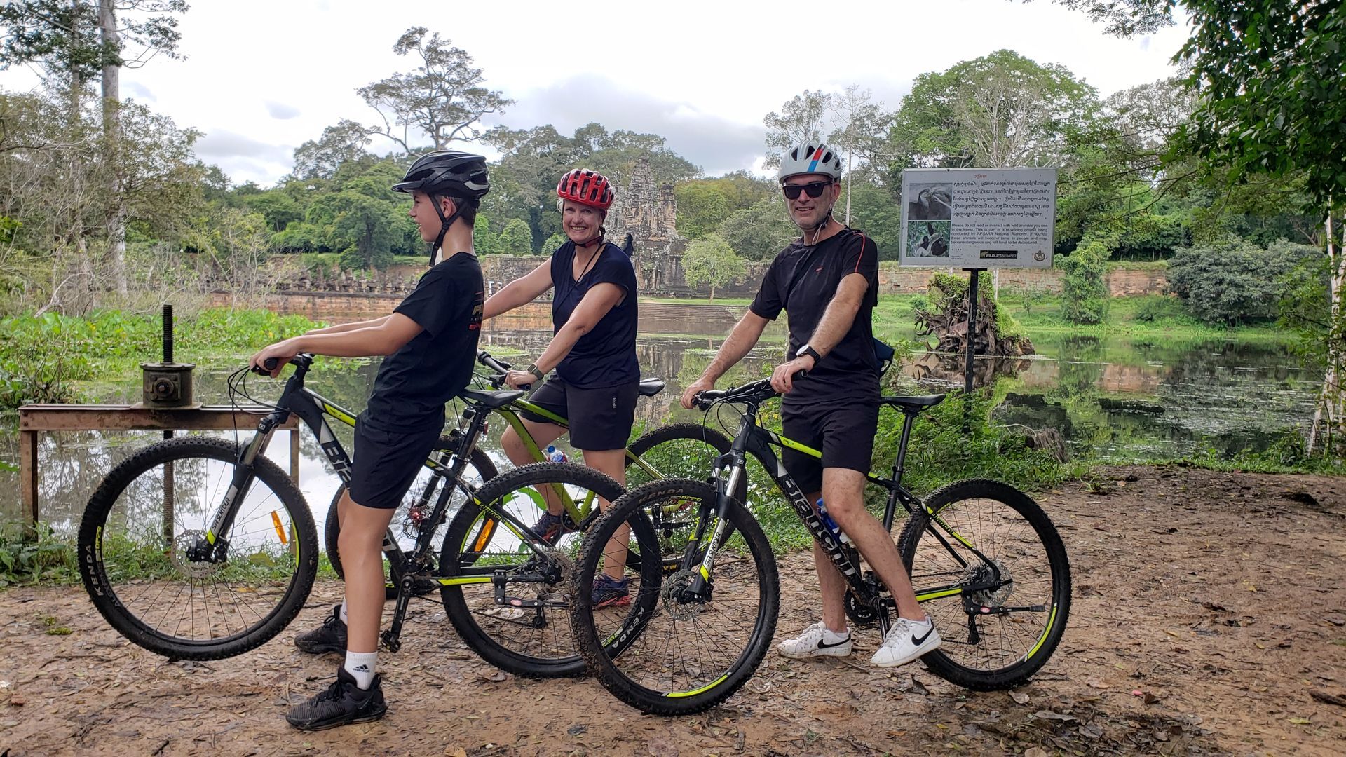 Traveler biking through Angkor jungle trails on a private cycling adventure past ancient temples and lush forests in Cambodia.