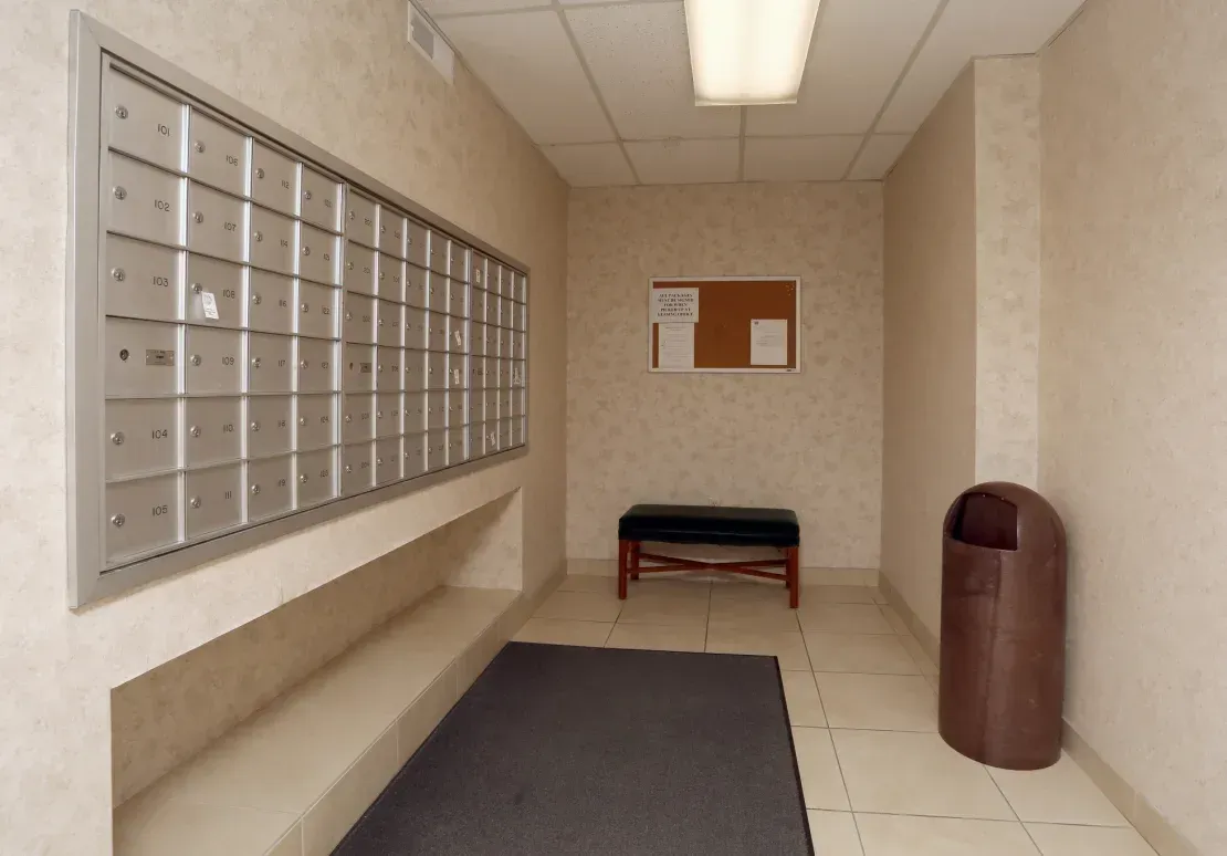 A mail room with a bench and a trash can