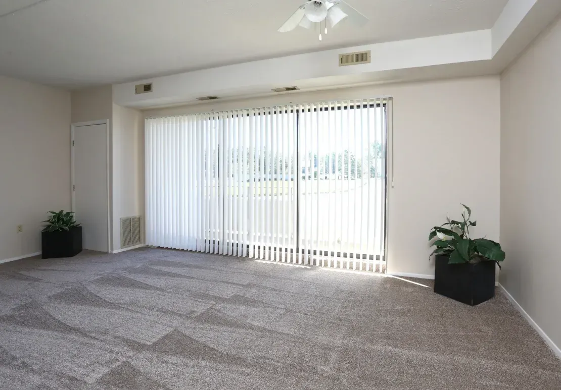 An empty living room with sliding glass doors and a ceiling fan.