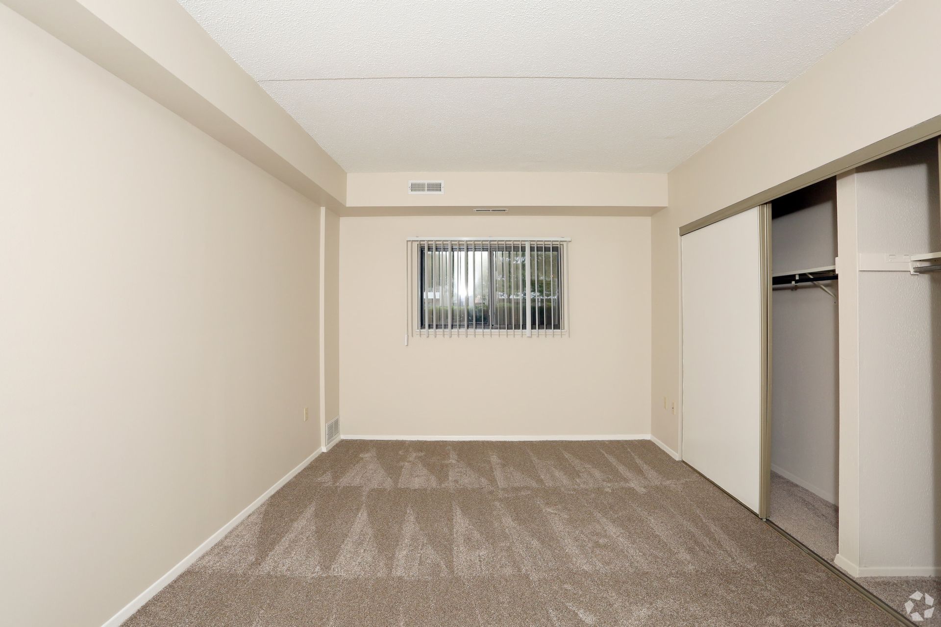 An empty room with a window and sliding doors