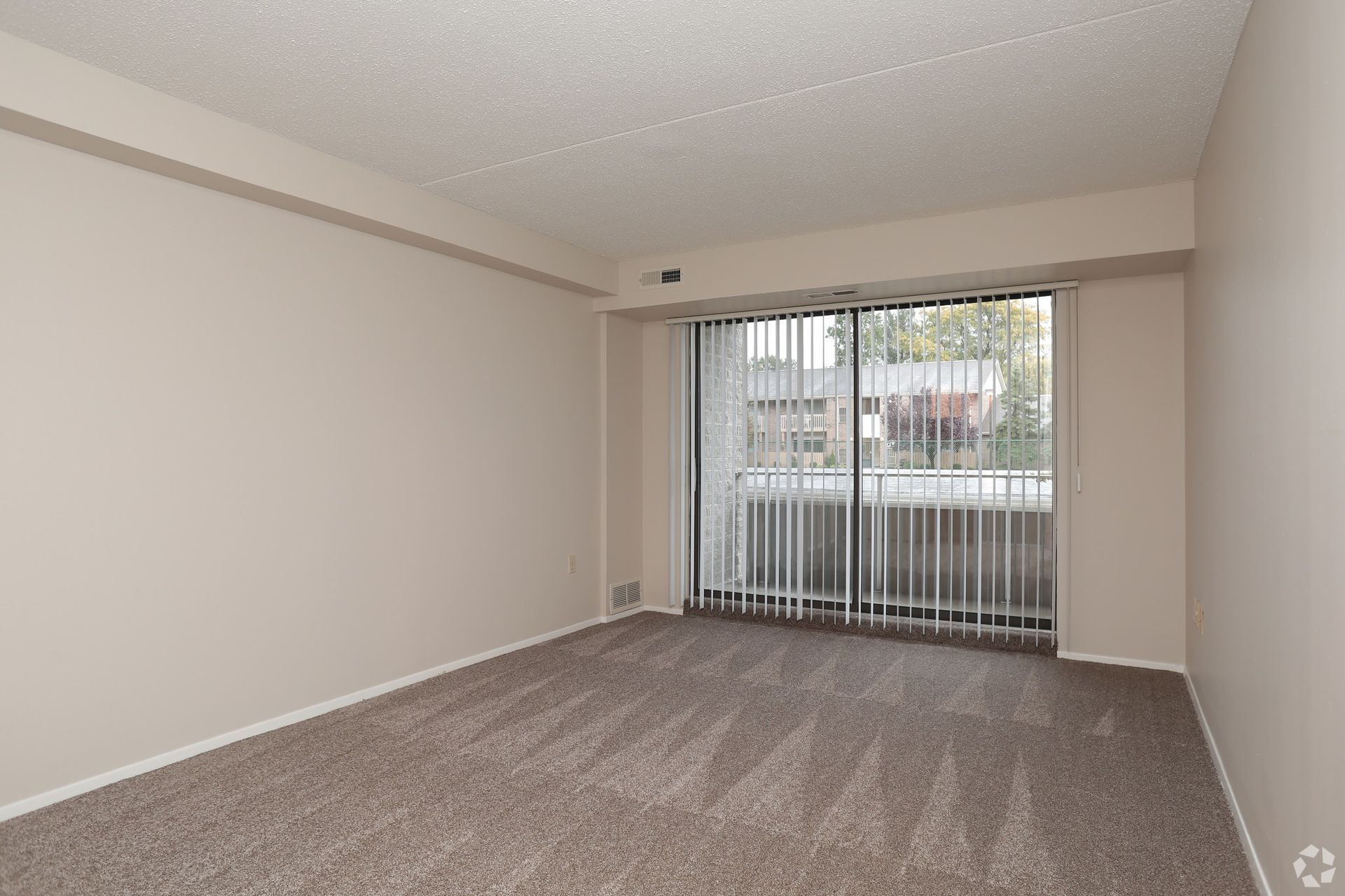 An empty living room with a sliding glass door and a balcony.