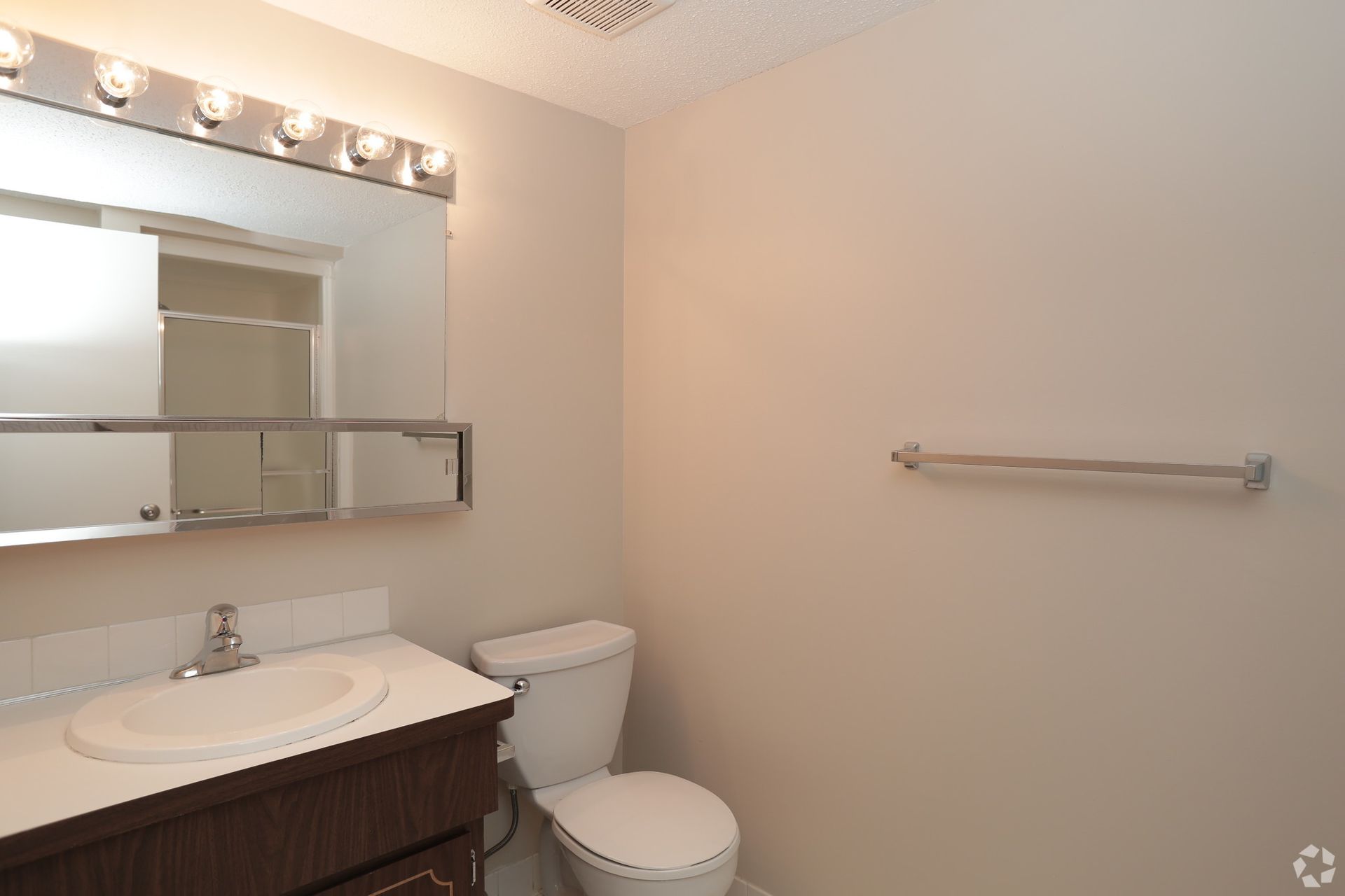 A bathroom with a toilet , sink and mirror