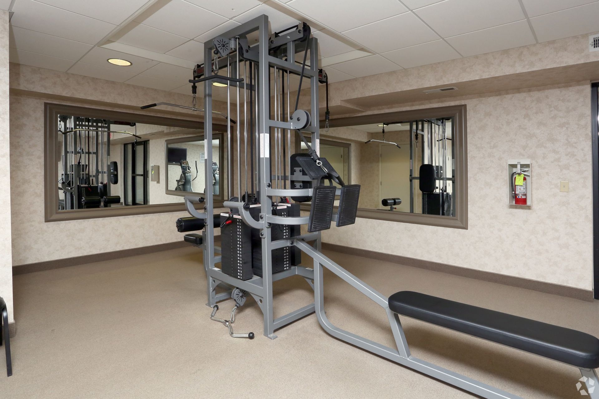 A gym with a lot of equipment and a fire extinguisher
