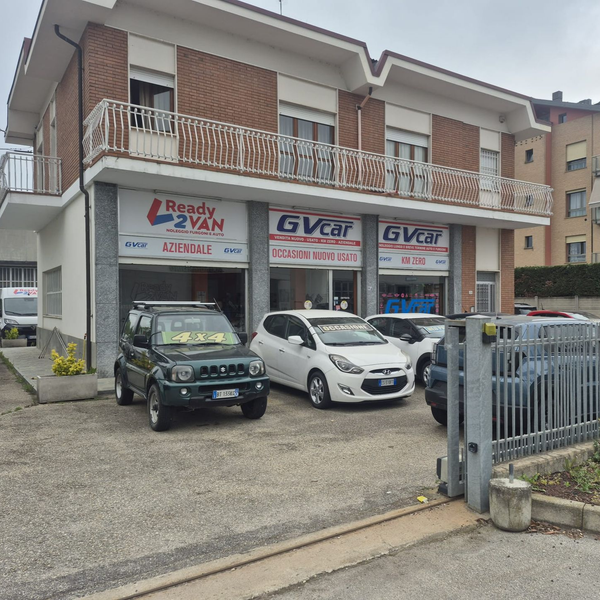 Concessionaria di automobili con auto parcheggiate davanti a un edificio in mattoni a due piani e a delle aree adibite a garage.