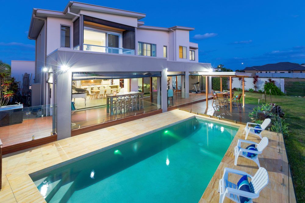 Modern Multilevel House Exterior With Pool At Dusk — Professional Pool Builder in Tumut, NSW