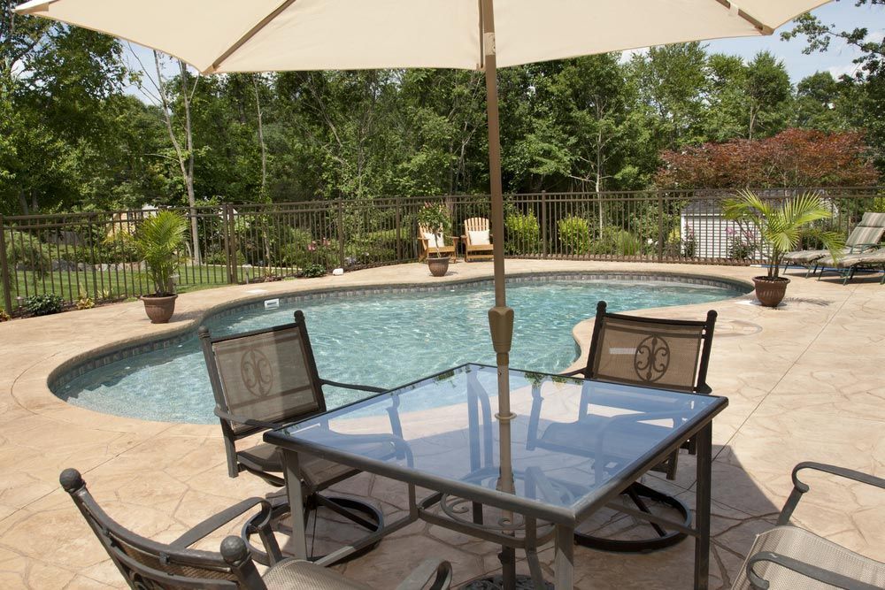 A View Of A Luxury Salt Water Pool And Patio In A Residential Backyard Through Patio Furniture