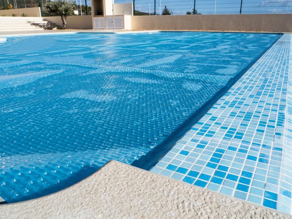 The Cover Of Swimming Pool Which Also Lets The Pool Heat Up From The Sun — Professional Pool Builder in Junee, NSW