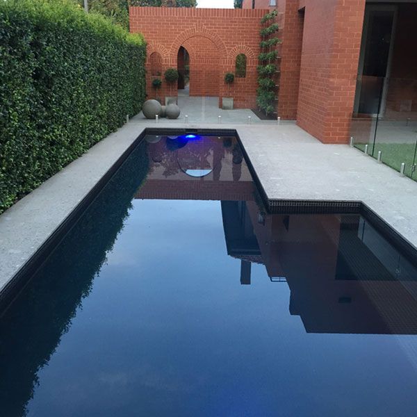 Concrete lap pool outside heritage building in early morning light.