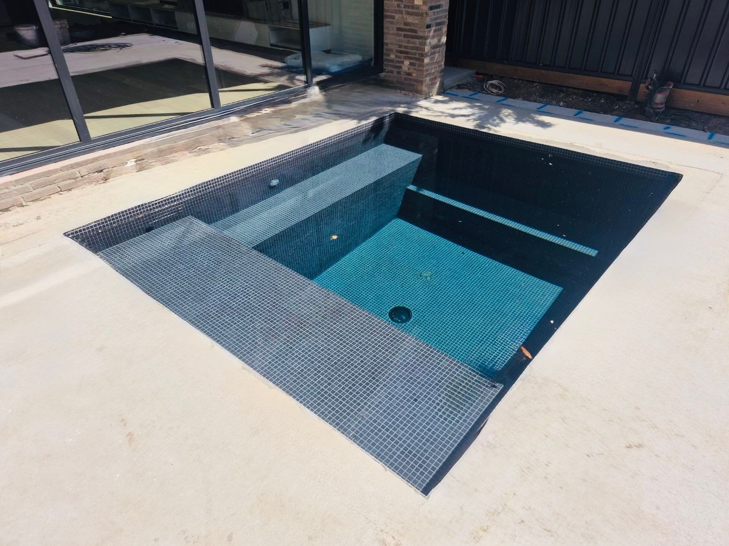 Hand Holding Blue and Yellow Brush-like Toys in Front of a Small Blue Pool — Pool Cleaning Services in Wagga Wagga, NSW