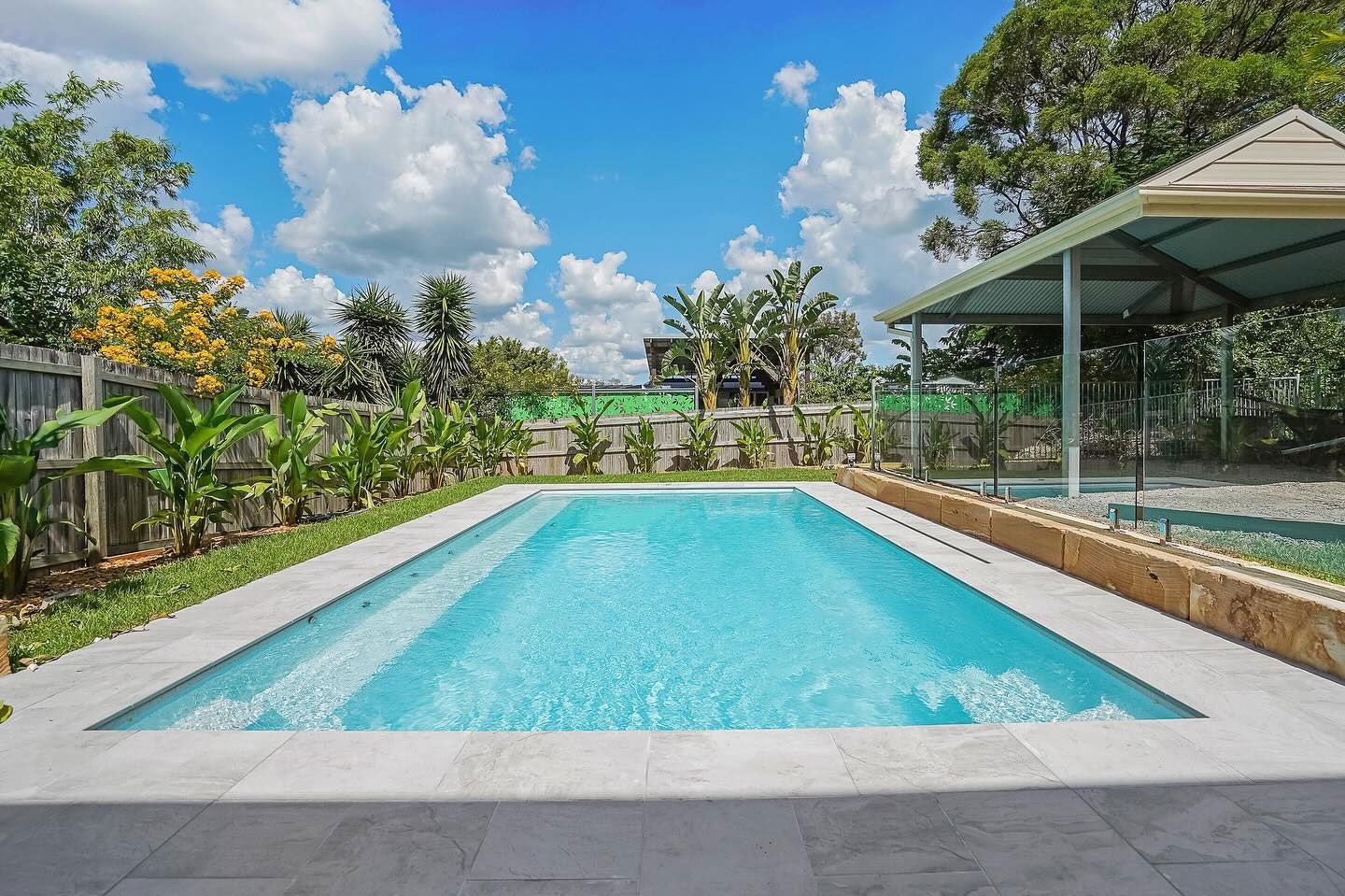 Outdoor Swimming Pool Beside a Modern House, With a Glass-covered Patio — Professional Pool Builder in Wagga Wagga, NSW