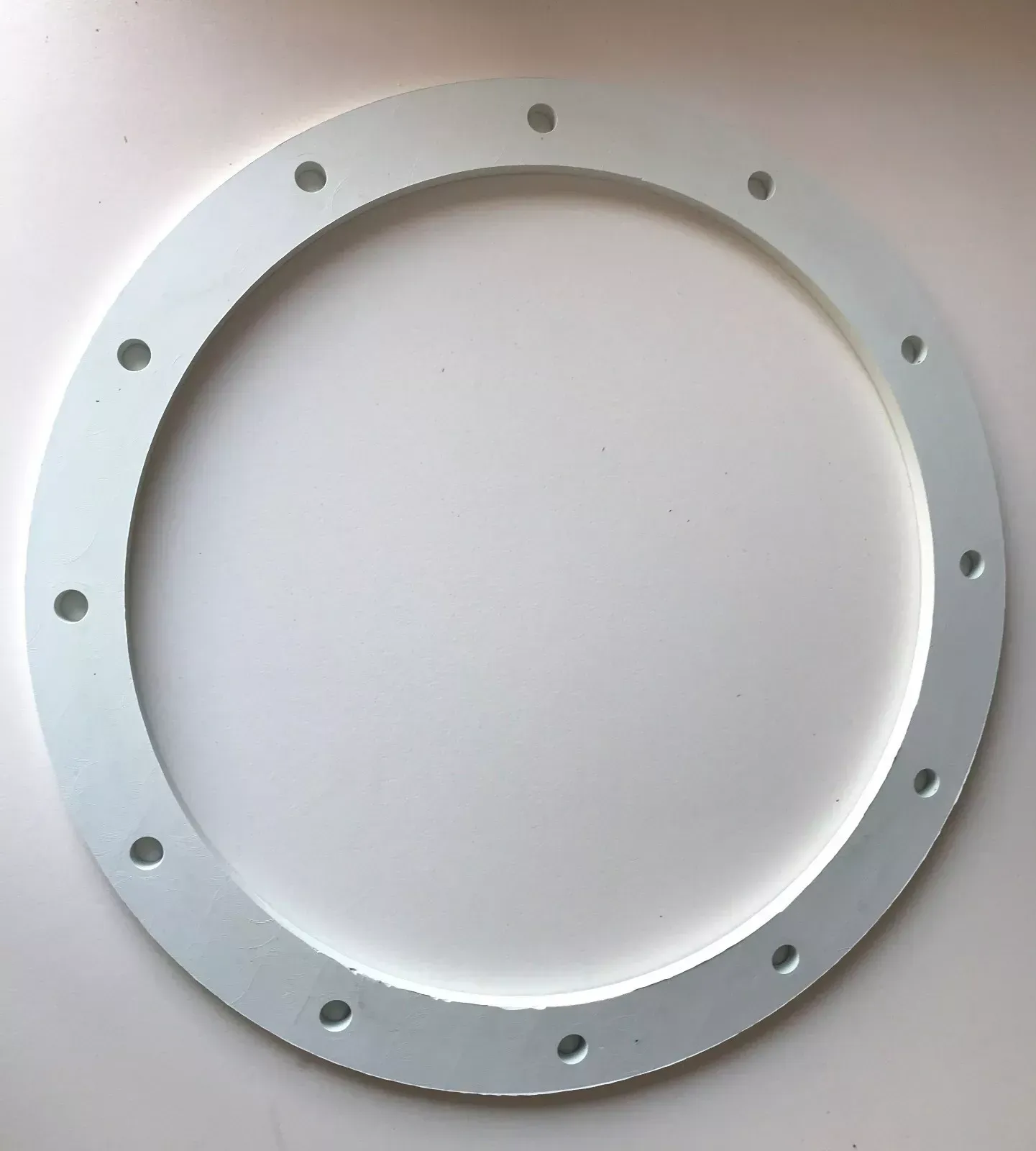 White circular flange with evenly spaced bolt holes.