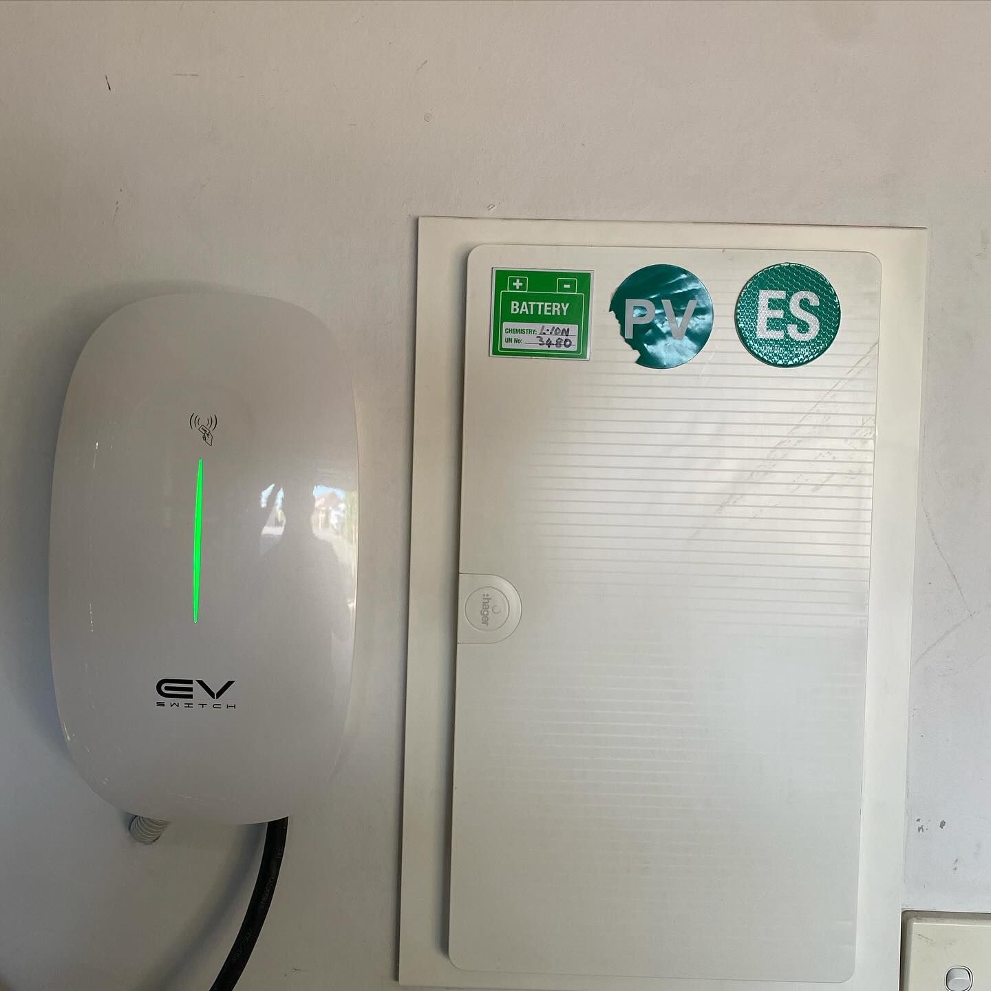 Wall-mounted electric vehicle charger beside an electrical enclosure