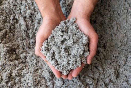 A person is holding a pile of cellulose insulation in their hands.