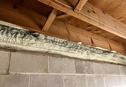A rim joist with a lot of foam on it and a block foundation.