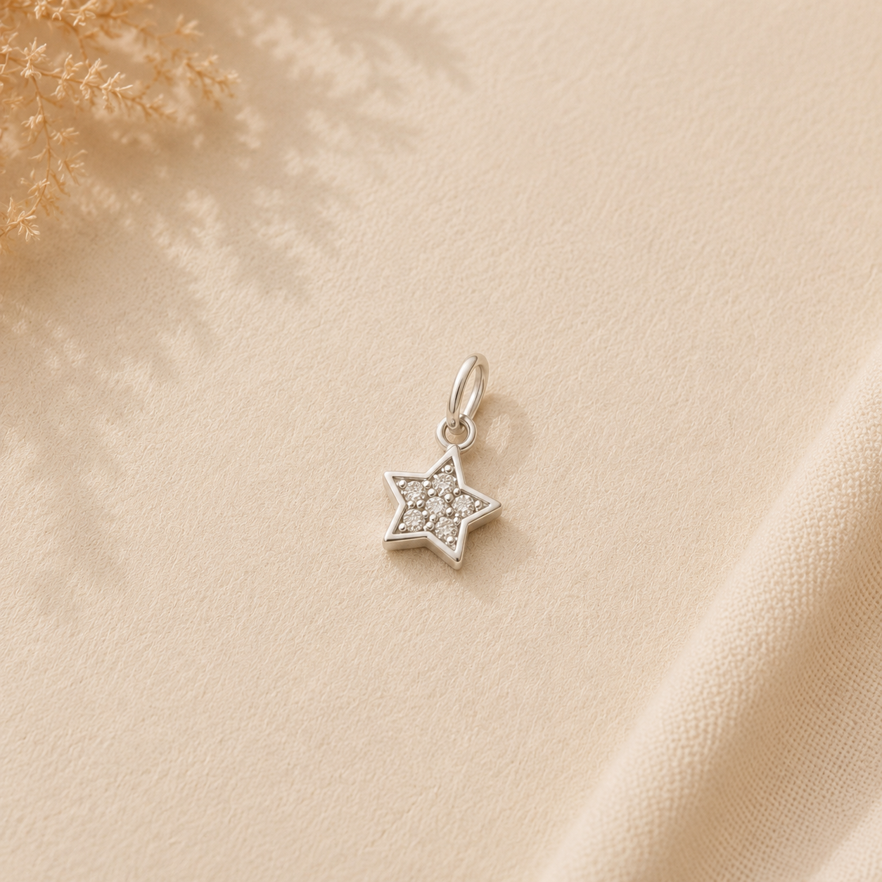 Colgante plateado en forma de estrella sobre un fondo beige texturizado con suaves sombras.