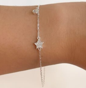 Pulsera con dije de estrella plateada en la muñeca