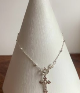 Collar de plata con colgante de cruz en un cono de exhibición blanco.