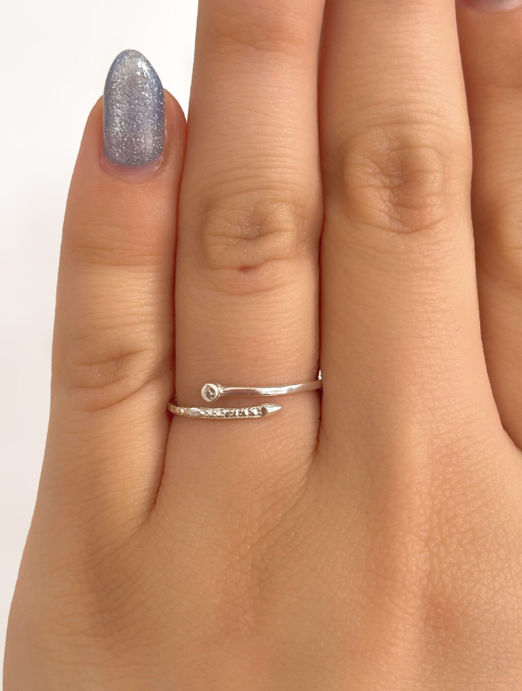 Mano con esmalte de uñas plateado brillante luciendo dos finos anillos plateados