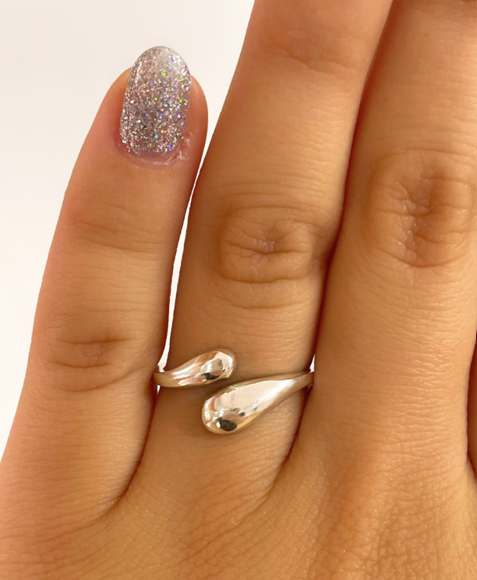 Mano con esmalte de uñas lavanda brillante luciendo un anillo abstracto plateado