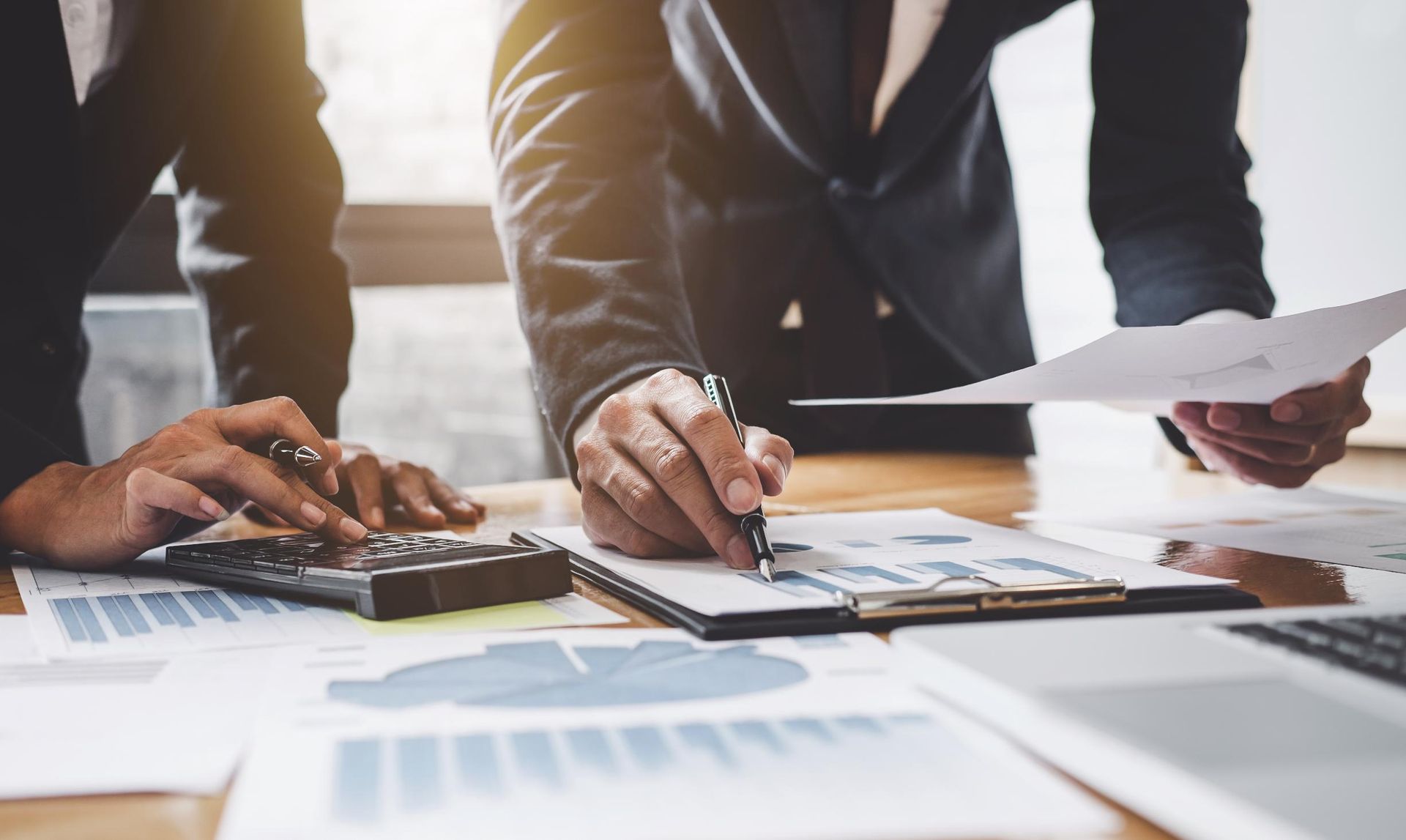 Two business people are sitting at a table looking at papers — Sunshine Coast Financial Advisers in Maroochydore, QLD
