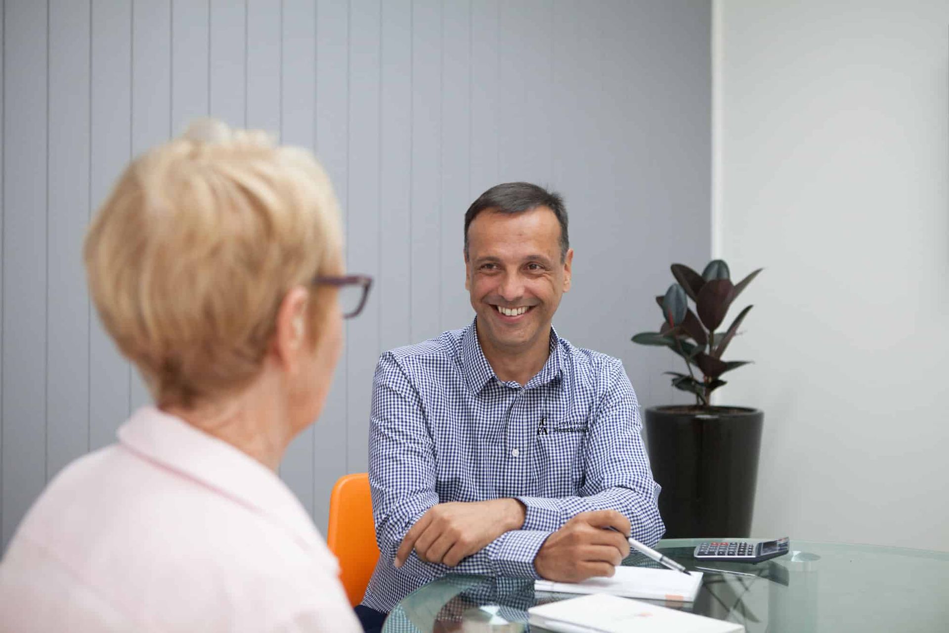 A Man and A Woman Are Sitting at A Table Having a Conversation — Sunshine Coast Financial Advisers in Maroochydore, QLD
