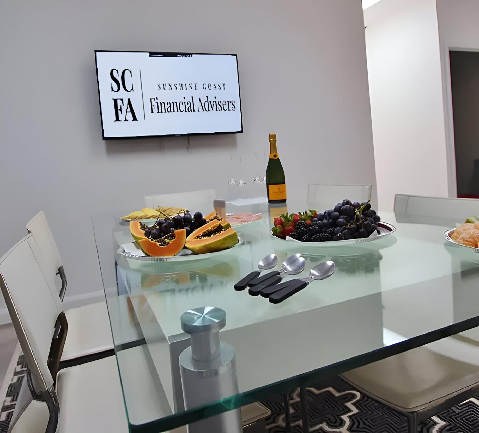 A Dining Room Table with Plates of Fruit and A Bottle of Champagne — Sunshine Coast Financial Advisers in Maroochydore, QLD