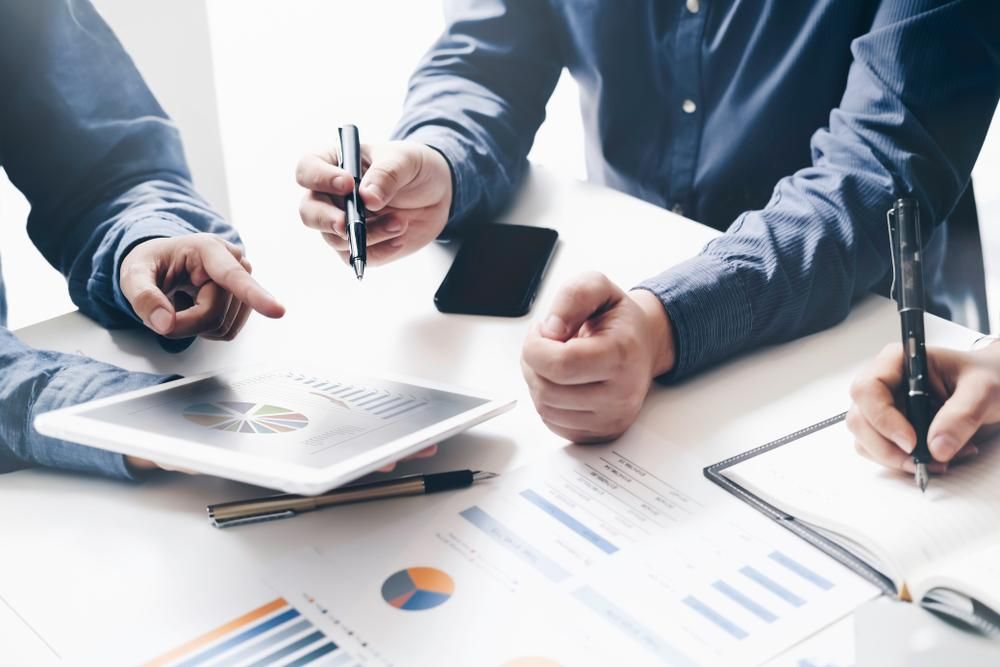 A Group of People Are Sitting at A Table Looking at A Tablet — Sunshine Coast Financial Advisers in Maroochydore, QLD