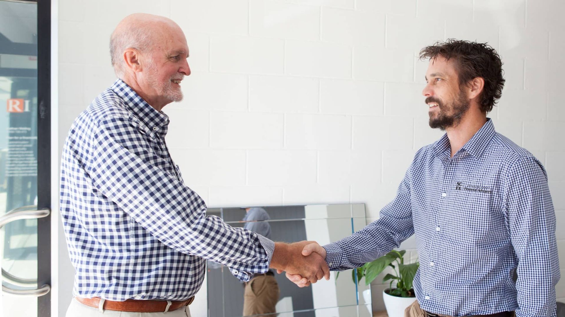Men Are Shaking Hands in A Room — Sunshine Coast Financial Advisers in Maroochydore, QLD