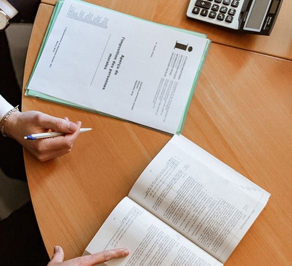 A Person Is Sitting at A Table with Papers and A Calculator — Sunshine Coast Financial Advisers in Maroochydore, QLD