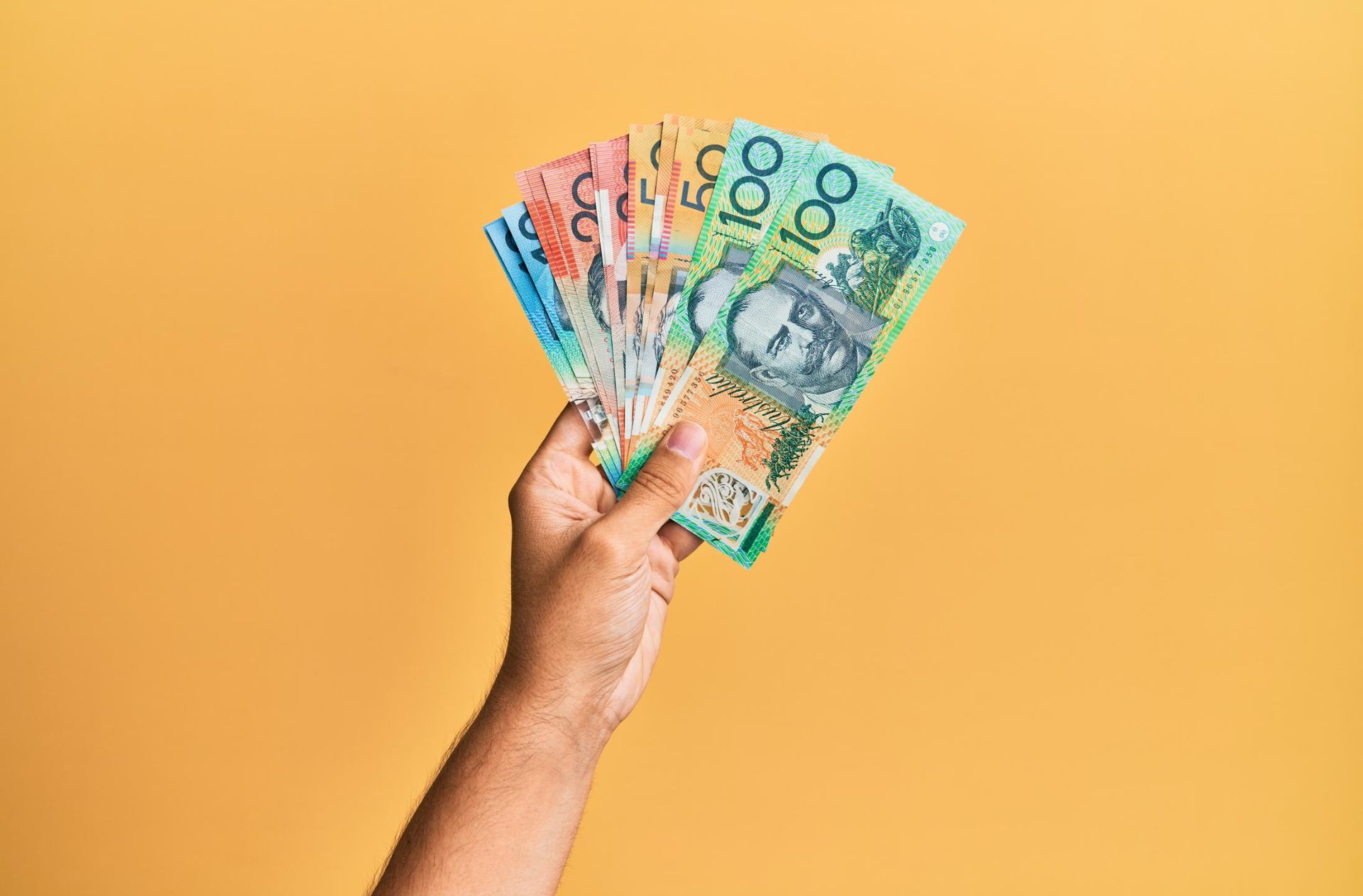 A Person Is Holding a Fan of Australian Dollars on A Yellow Background — Sunshine Coast Financial Advisers in Caboolture, QLD
