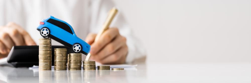 A Person Is Sitting at A Table with A Stack of Coins and A Toy Car — Sunshine Coast Financial Advisers in Caboolture, QLD