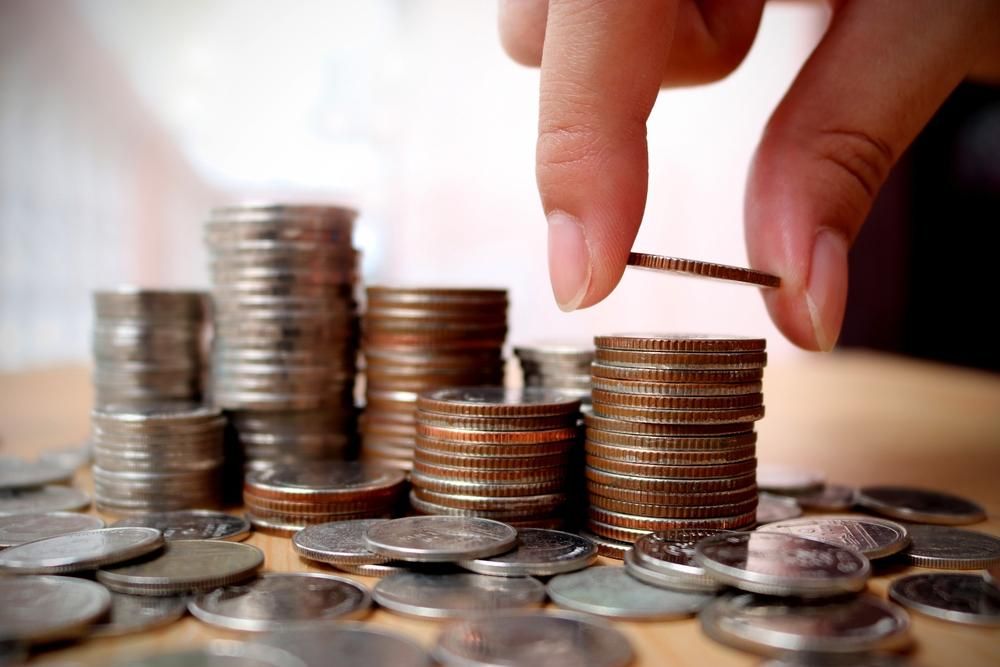 A Person Is Stacking Coins on Top of Each Other on A Table — Sunshine Coast Financial Advisers in Noosa, QLD