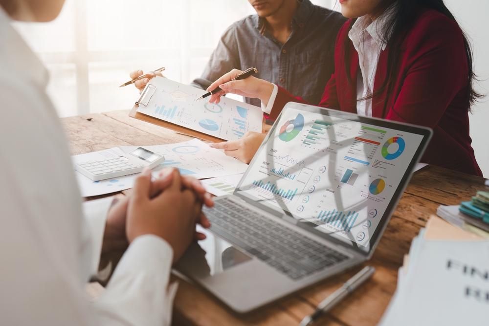 A Group of People Are Sitting at A Table Looking at A Laptop Computer — Sunshine Coast Financial Advisers in Maroochydore, QLD